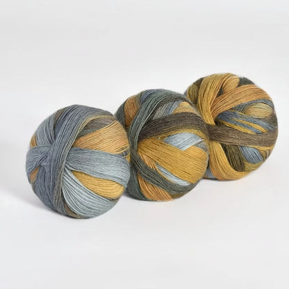 Three skeins of yarn with a mix of gray and yellow colors on a white background.